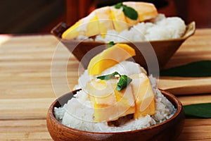 Mango sticky rice is put in a wooden container placed on a brown