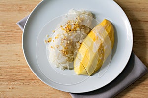 Mango with sticky rice in white plate on wooden table