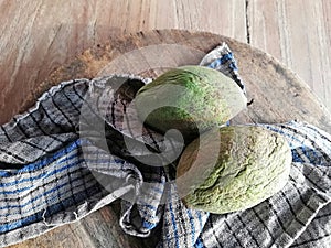 Mangos fruit in green color, placed on brown wooden background