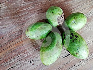 Mangos fruit in green color, placed on brown wooden background