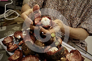 Mangosteen and cross section showing the thick purple skin and white flesh of the queen of fruits