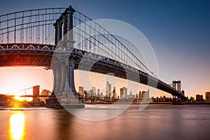 Manhattan Bridge framing New York skyline at sunset