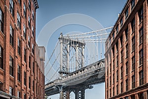 Manhattan bridge seen from narrow buildings on a sunny day