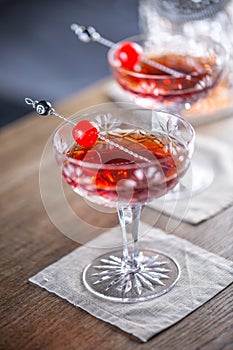 Manhattan classic cocktail as a short drink aperitif with whisky, vermouth, angostura aromatic bitter and cherry garnish