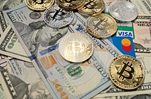 Manhattan, New York/USA - March 26. 2021: Bitcoin on dollar banknotes and Visa credit card next to Mastercard debit card. Crypto