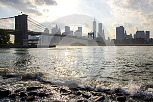 Manhattan skyline and Brooklyn bridge. East river waves. New York City.
