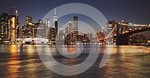 Manhattan skyline and Brooklyn Bridge reflected in water at dusk, New York City, USA