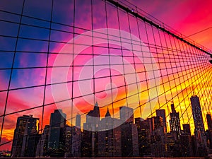 Manhattan skyline through Brooklyn Bridge at sunset