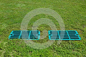 Manhole drainage grates on the lawn with green grass septic tank cover.