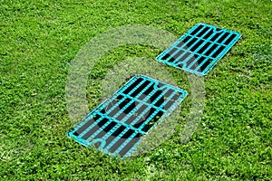 Manhole drainage grates on the lawn with green grass septic tank cover. photo