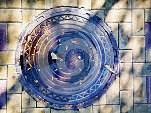 Manhole, iron hatch, laz, wheel in the sunny street