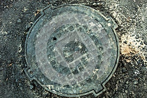 Manhole with metal cover in asphalt surface