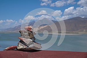 Mani stone pile in Tibet against tranquil lake