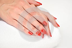 Manicure - Beautiful manicured woman`s nails with red nail polish on soft white towel