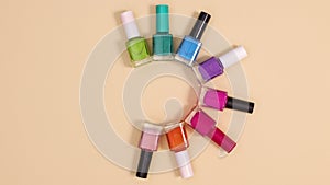 Manicure concept of different colors nail polish bottles appear on beige background. Stop motion flat lay