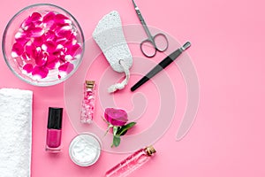 Manicure equipment with nail polish and rose petals pink background top view space for text