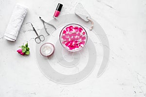 Manicure equipment with nail polish and rose petals white stone background top view mockup