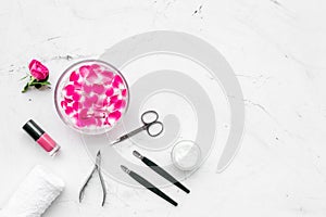 Manicure equipment with nail polish and rose petals white stone background top view mockup
