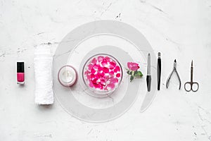 Manicure equipment with nail polish and rose petals white stone background top view mockup