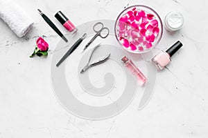 Manicure equipment with nail polish and rose petals white stone background top view mockup