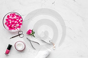 Manicure equipment with nail polish and rose petals white stone background top view mockup