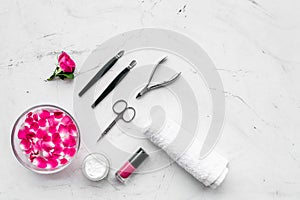 Manicure equipment with nail polish and rose petals white stone background top view mockup