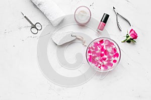 Manicure equipment with nail polish and rose petals white stone background top view mockup