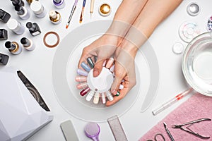 Manicure - the girl herself does, watching the nails with the help of a tool on a white background. Concept of beauty salons and n