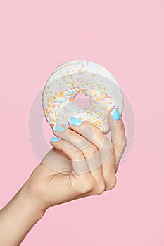 Manicure. Hand With Blue Nails Holding Donut