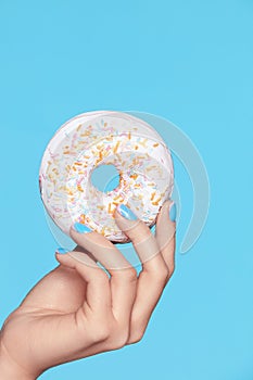 Manicure. Hand With Blue Nails Holding Donut