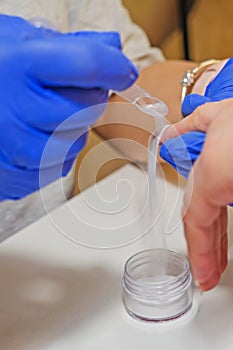 Manicure master applying acrylic powder on the woman long nails in a beauty salon