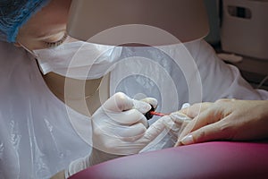 Manicure. Master manicurist varnishes the gel on the female nails. Local lighting.