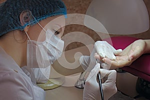 Manicure. Master manicurist varnishes the gel on the nails of a female client.