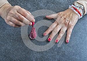 Manicure. Old Woman Hands Polishing Nails With Red Nail Polish In Beauty Salon