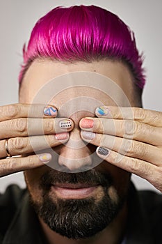 Manicure with a pattern on the fingers of a man, purple hair on the head of a guy. Hand nail care