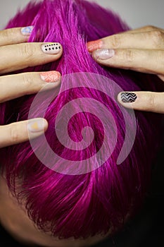 Manicure with a pattern on the fingers of a man, purple hair on the head of a guy. Hand nail care