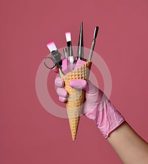 Manicure and pedicure abstract concept. Hand hold waffles cone with instruments for nails salon and spa brush nail file