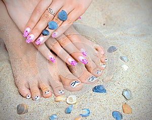 Manicure and pedicure against the background of sea sand and seashells.