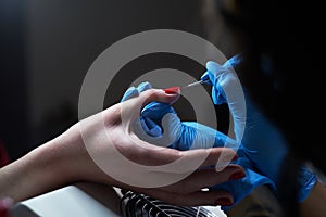 Closeup hands. Manicure procedure in progress - Beautician master applying color nail polish.