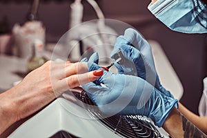 Closeup hands. Manicure procedure in progress - Beautician master applying color nail polish.