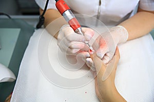 Manicure in process.Closeup shot of a woman in a nail salon receiving a manicure by a beautician with nail file. Woman getting