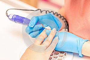 Manicure process. The manicure master polishes the nail using a machine. Close up manicure process