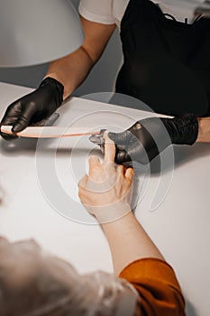 Manicure process. The master does a manicure. Two women in medical masks. Manicure master makes nails cute pretty young woman in