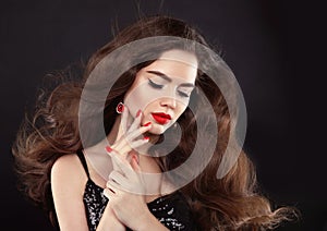 Manicure. Red lips makeup. Beautiful Brunette girl with long blowing shiny wavy hair. Fashion earring jewelry. Elegant model with