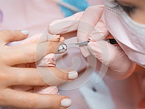 Manicure salon master drawing varnish on the nail tip with a thin brush. Professional manicure in beauty salon. Hygiene