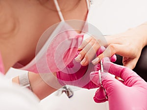 Manicure salon master removes cuticles with nail scissors. Woman getting nail manicure. Professional manicure in beauty