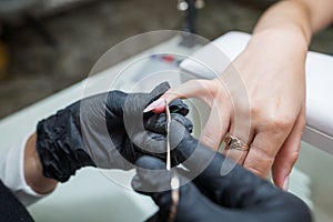 Manicure salon master removes cuticles with nail scissors. Woman getting nail manicure. Professional manicure in beauty salon.