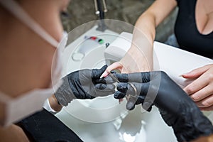 Manicure salon master removes cuticles with nail scissors. Woman getting nail manicure. Professional manicure in beauty salon.