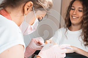 Manicure salon woman receiving a manicure by a beautician with nail file. Woman getting nail manicure. Professional