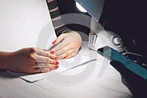 Manicure specialist in black gloves takes pictures of hands with red nails by phone. Manicurist in beauty salon. How shoot nail photo